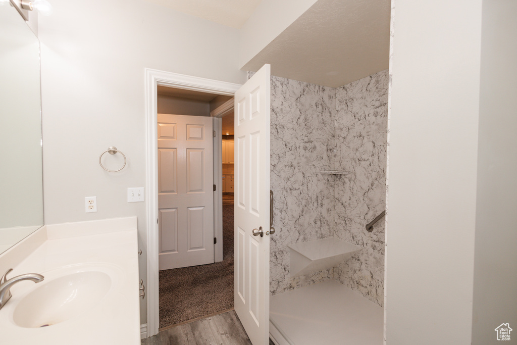 Bathroom featuring tiled shower, hardwood / wood-style flooring, and large vanity