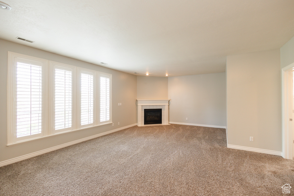 Unfurnished living room featuring a wealth of natural light and carpet flooring