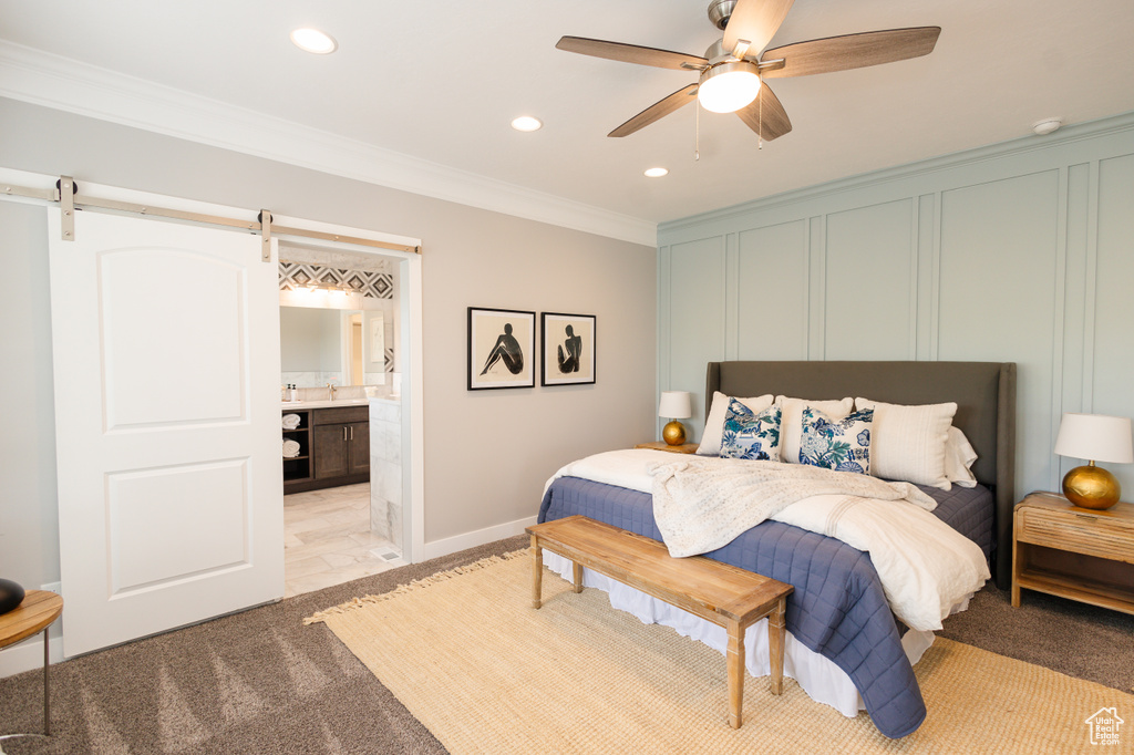 Carpeted bedroom featuring ensuite bathroom, ceiling fan, crown molding, and a barn door