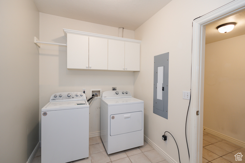 Laundry area with cabinets, hookup for an electric dryer, separate washer and dryer, and light tile flooring