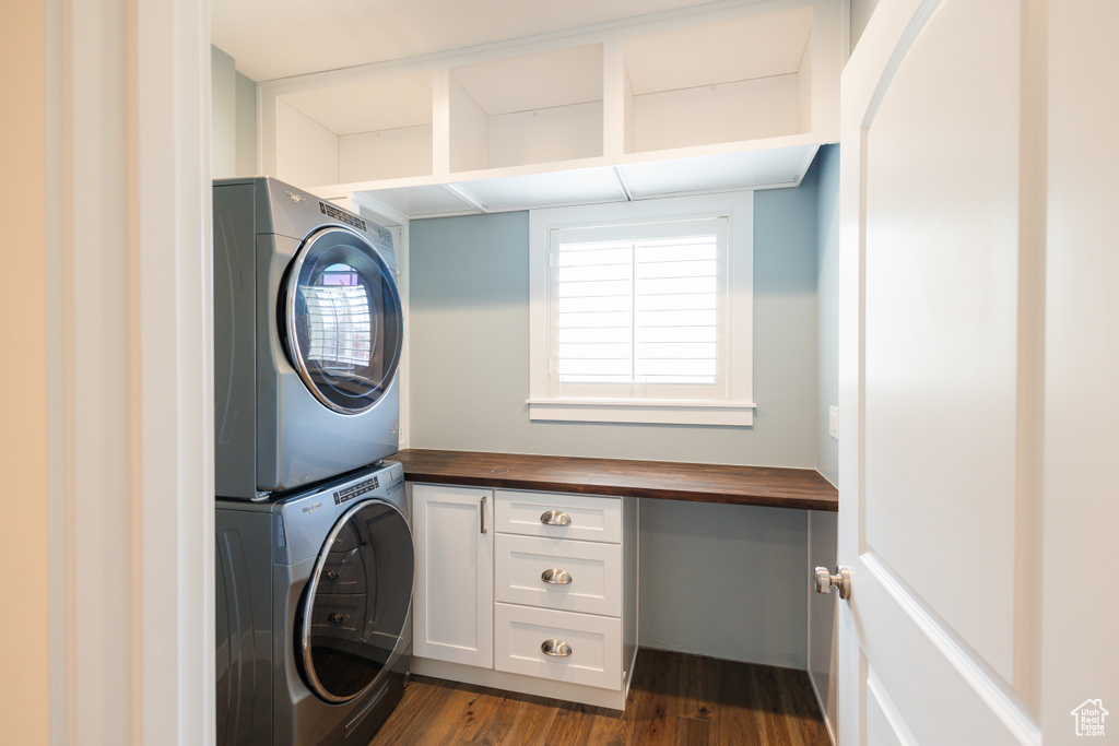 Laundry area with stacked washer and clothes dryer and dark hardwood / wood-style floors