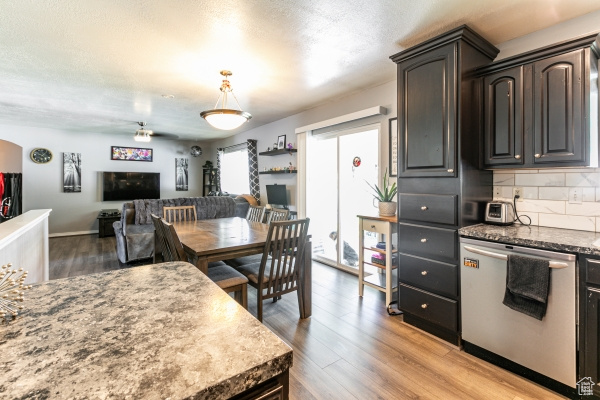 Kitchen with wood-type flooring, hanging light fixtures, stainless steel dishwasher, tasteful backsplash, and dark brown cabinetry