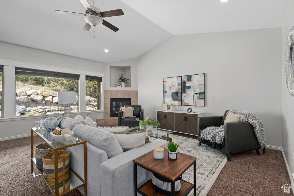 Living room featuring ceiling fan, a fireplace, vaulted ceiling, and carpet flooring
