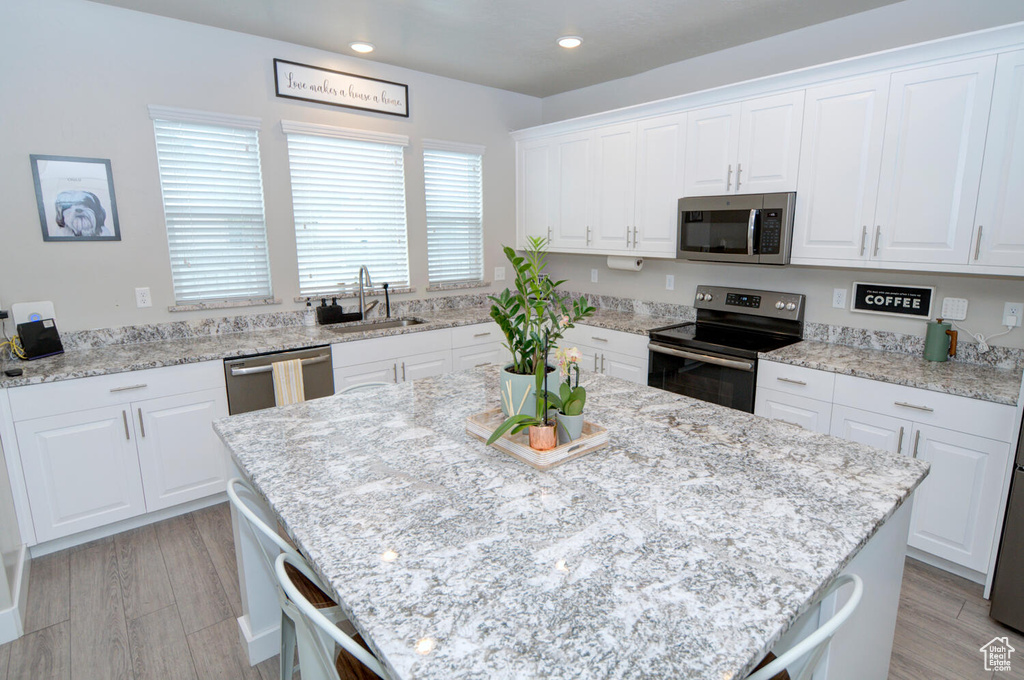 Kitchen featuring a center island, appliances with stainless steel finishes, white cabinetry, and sink