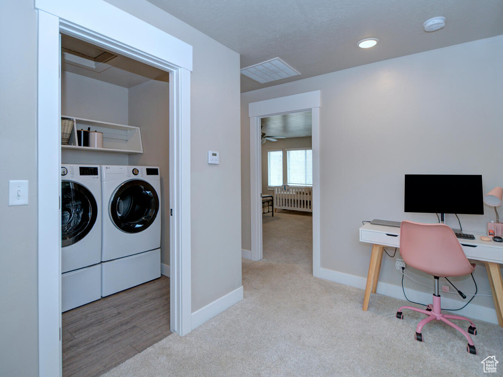 Clothes washing area featuring radiator heating unit, ceiling fan, light carpet, and washing machine and clothes dryer