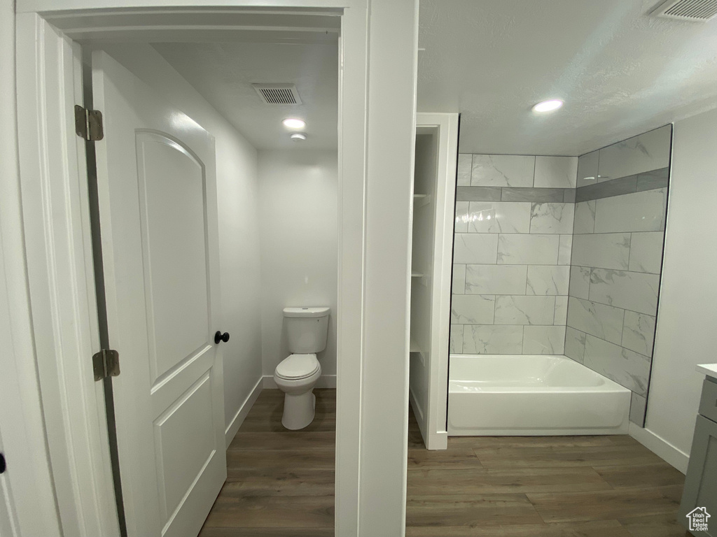 Full bathroom featuring tiled shower / bath, wood-type flooring, vanity, and toilet