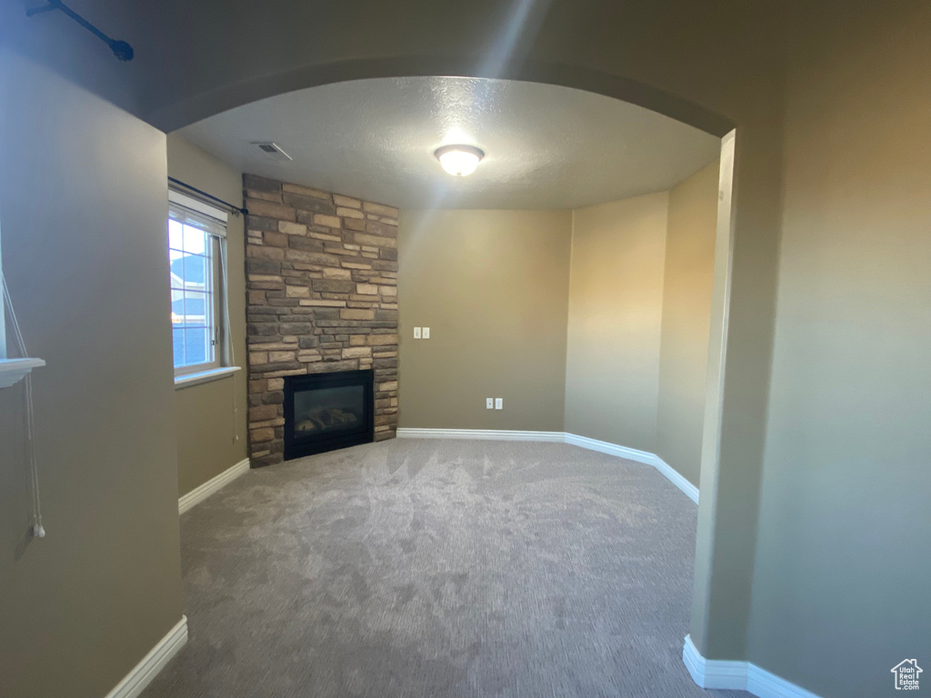 Unfurnished living room featuring carpet and a fireplace