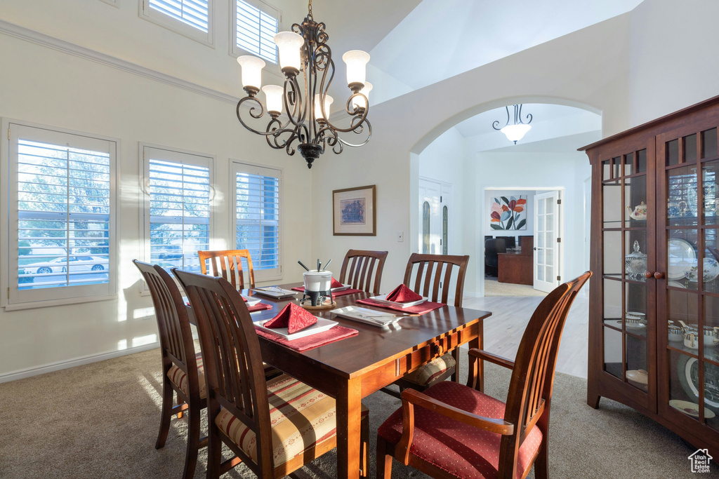 Carpeted dining room featuring high vaulted ceiling and an inviting chandelier