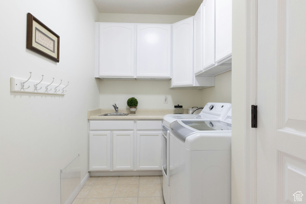 Laundry area featuring cabinets, sink, separate washer and dryer, and light tile flooring
