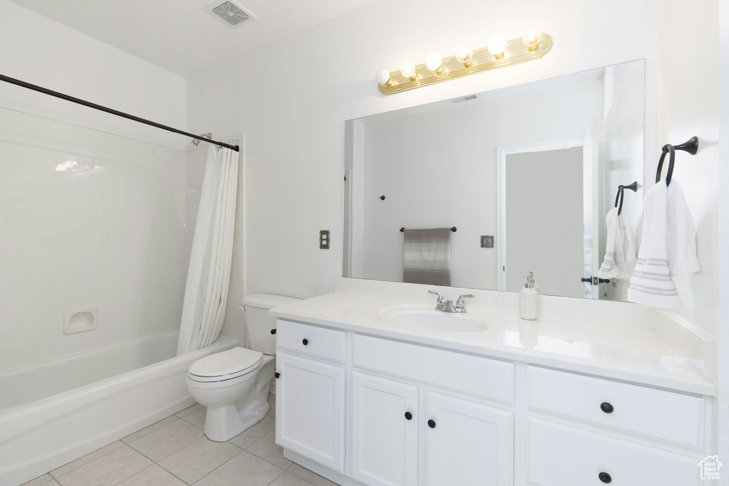 Full bathroom with tile flooring, oversized vanity, shower / tub combo, and toilet