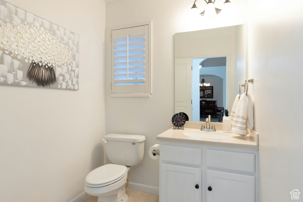 Bathroom featuring tile floors, oversized vanity, toilet, and a notable chandelier