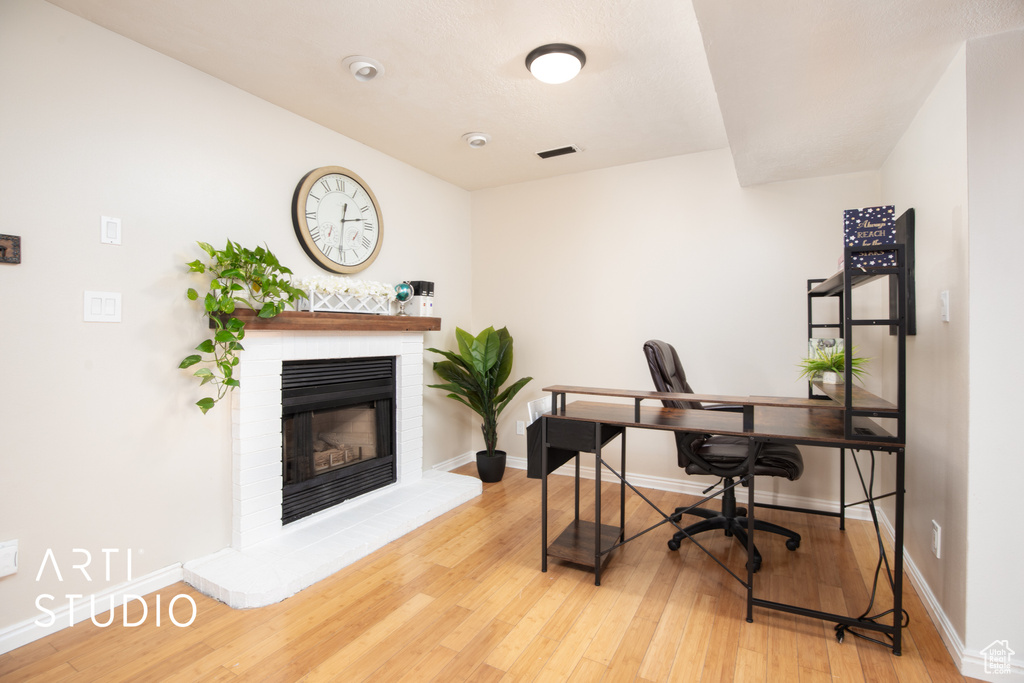 Office area with light hardwood / wood-style flooring and a fireplace