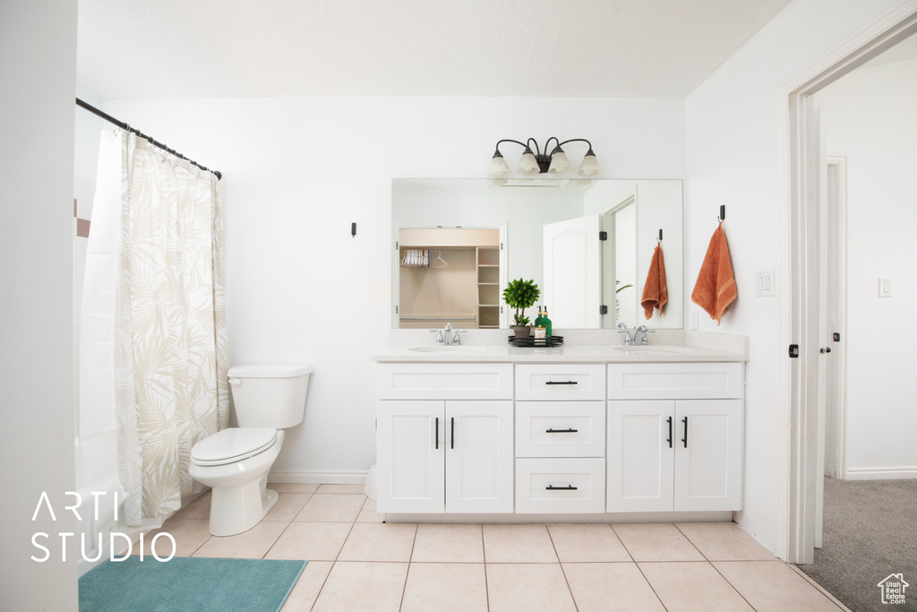 Bathroom with double sink, toilet, tile flooring, and large vanity