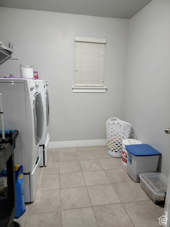Laundry area with light tile flooring and washing machine and clothes dryer