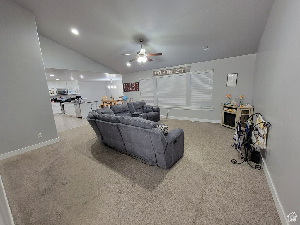 Living room featuring light colored carpet, high vaulted ceiling, and ceiling fan