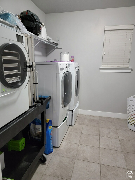 Clothes washing area featuring separate washer and dryer and light tile floors