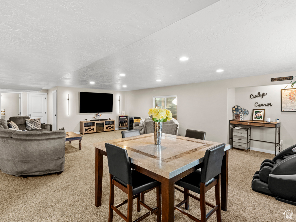 Dining space with light colored carpet and a textured ceiling
