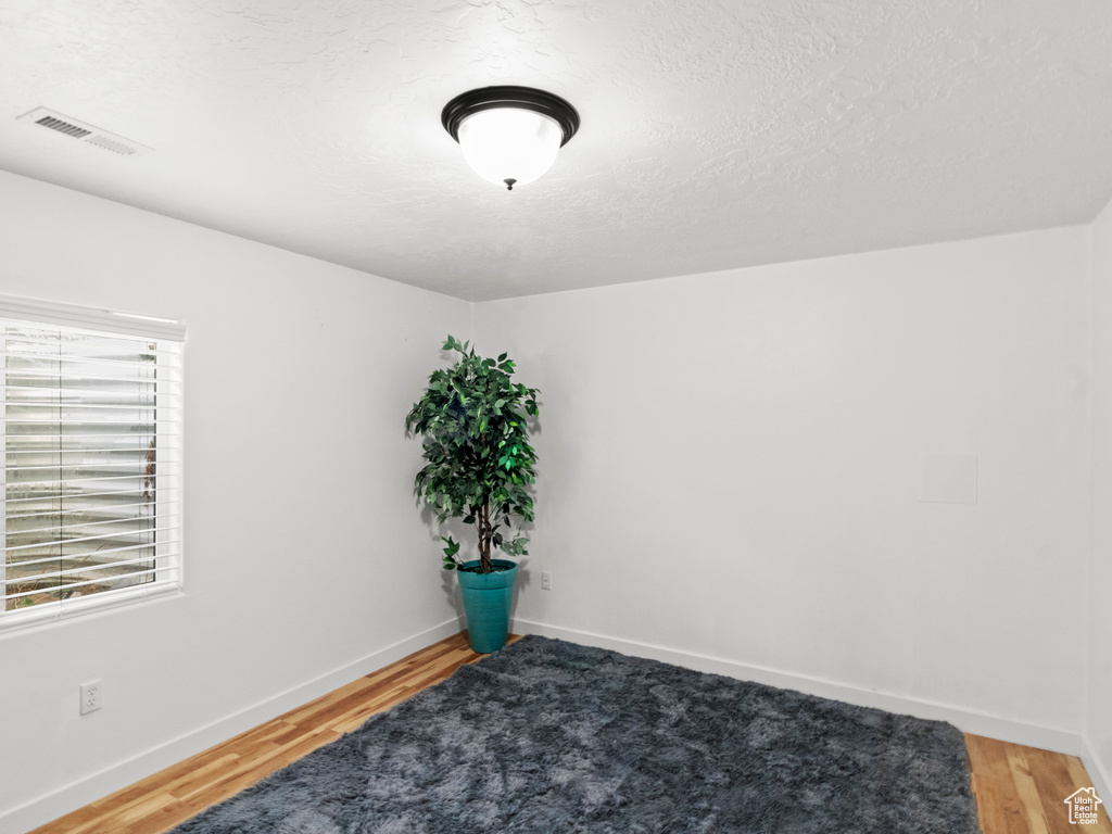 Empty room with a wealth of natural light and hardwood / wood-style flooring