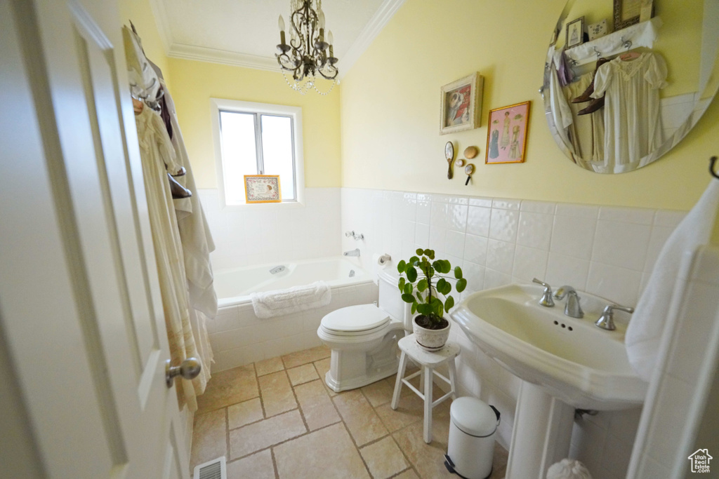 Bathroom featuring tile flooring, a notable chandelier, toilet, tiled bath, and ornamental molding