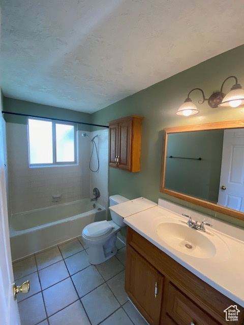 Full bathroom with tiled shower / bath combo, tile floors, vanity, and toilet
