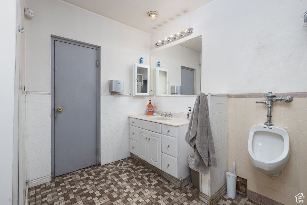 Bathroom with tile flooring, tile walls, oversized vanity, tasteful backsplash, and a bidet