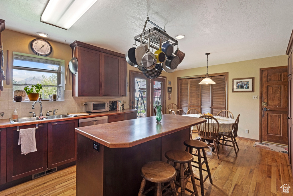 Kitchen featuring a kitchen island, sink, tasteful backsplash, and light wood-type flooring