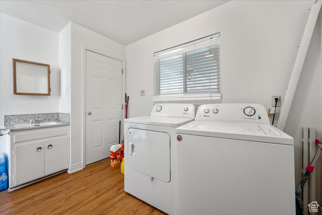 Laundry room with independent washer and dryer, sink, and light wood-type flooring