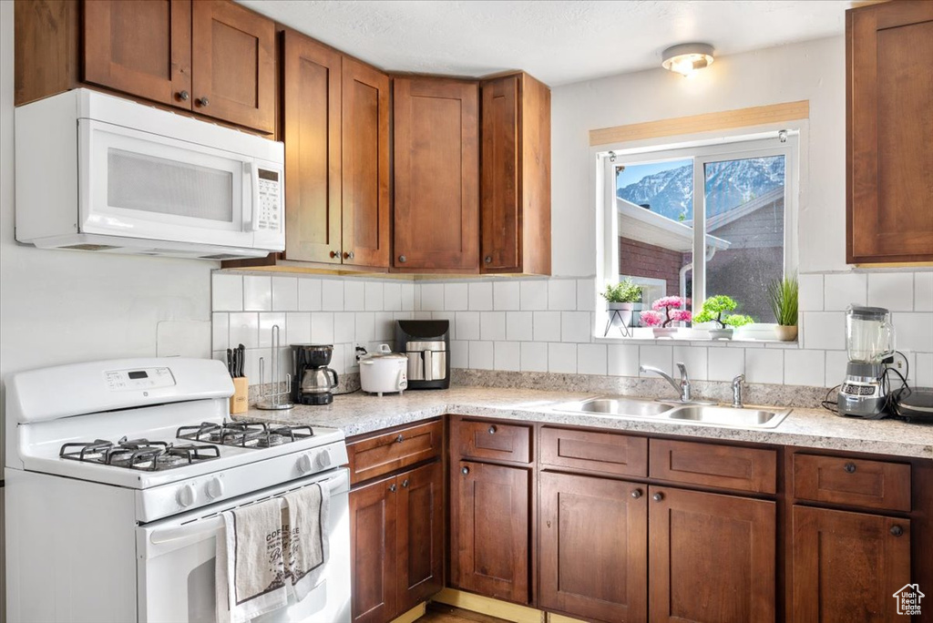 Kitchen with sink, white appliances, and backsplash