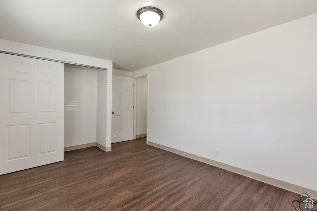 Unfurnished bedroom with dark hardwood / wood-style flooring and a closet