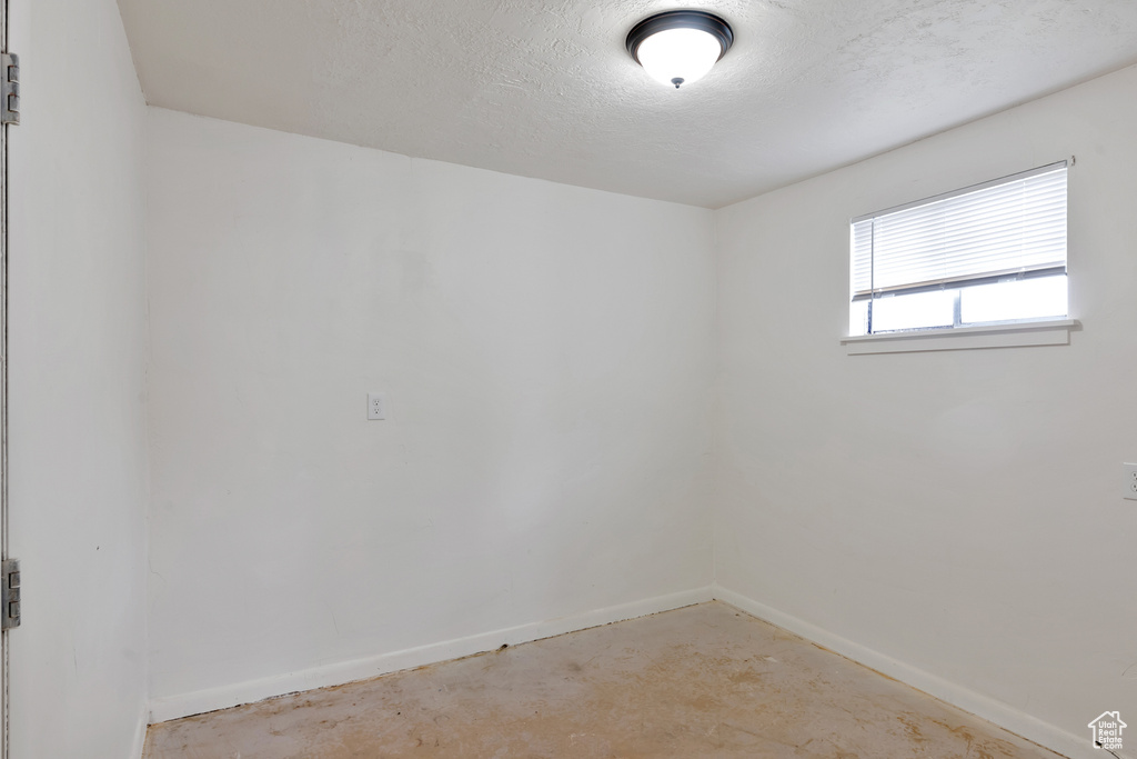 Empty room with concrete flooring and a textured ceiling