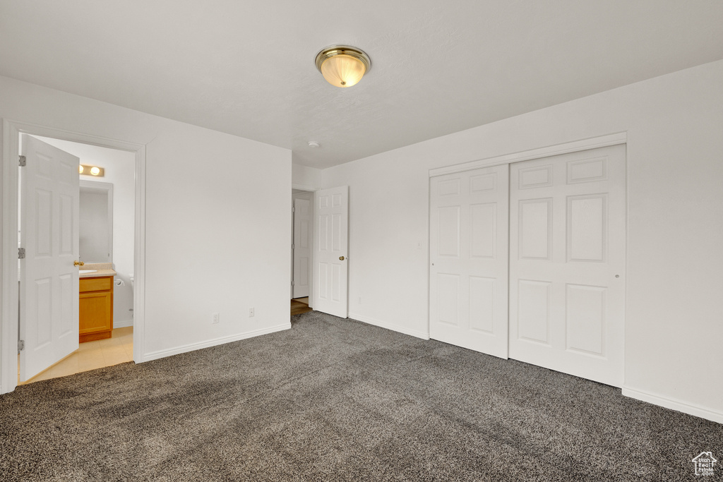 Unfurnished bedroom with ensuite bath, a closet, and carpet floors