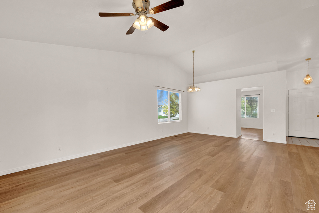 Spare room with a healthy amount of sunlight, light hardwood / wood-style floors, and vaulted ceiling