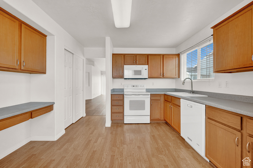 Kitchen featuring light hardwood / wood-style flooring, white appliances, and sink