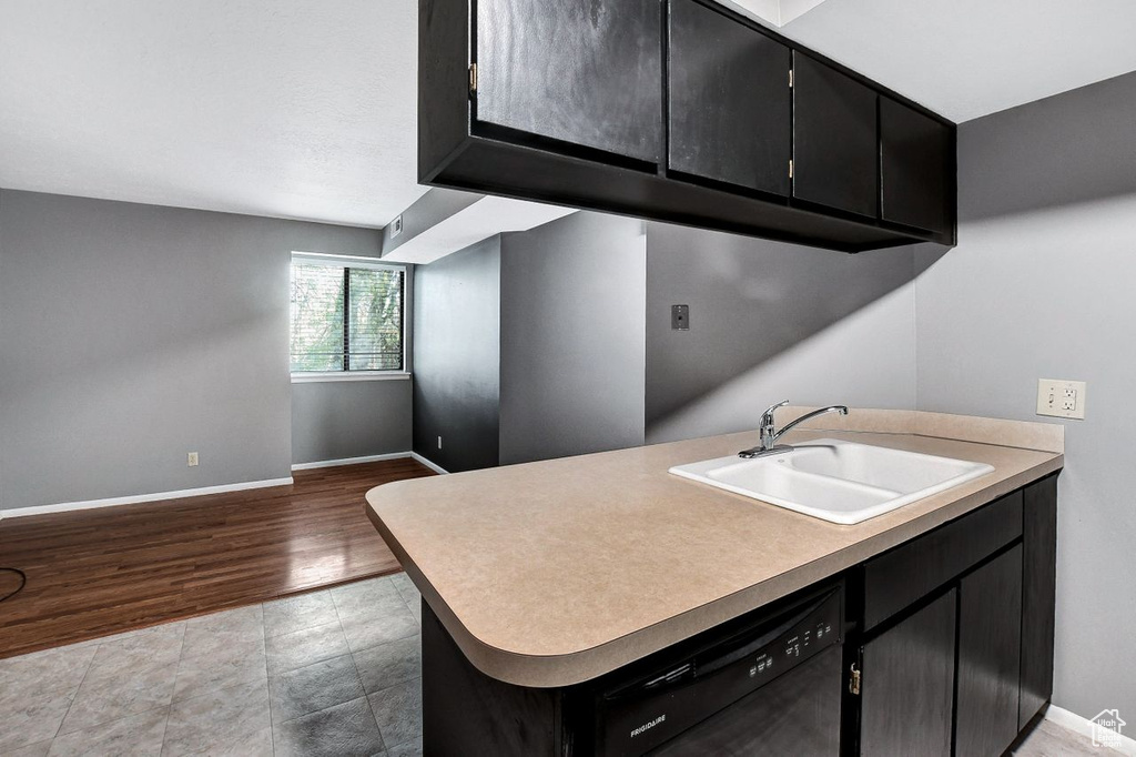 Kitchen featuring black dishwasher, kitchen peninsula, light hardwood / wood-style flooring, and sink