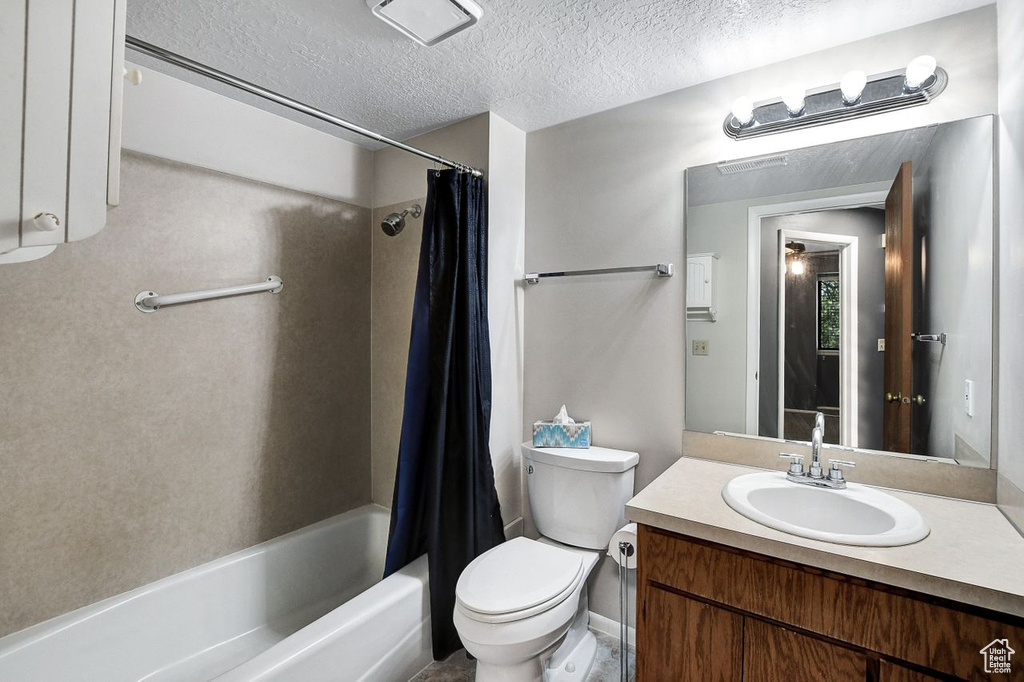 Full bathroom with tile flooring, shower / bath combo with shower curtain, large vanity, a textured ceiling, and toilet