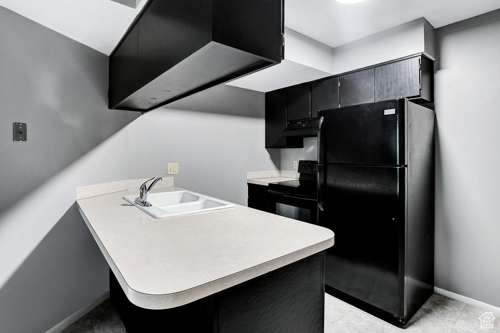 Kitchen featuring sink, ventilation hood, light tile floors, and black appliances