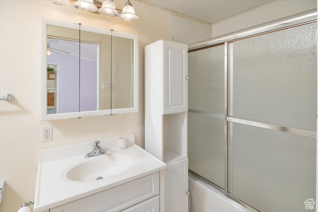 Bathroom with ceiling fan, shower / bath combination with glass door, and large vanity