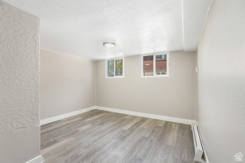 Spare room featuring a baseboard heating unit, a textured ceiling, and hardwood / wood-style floors