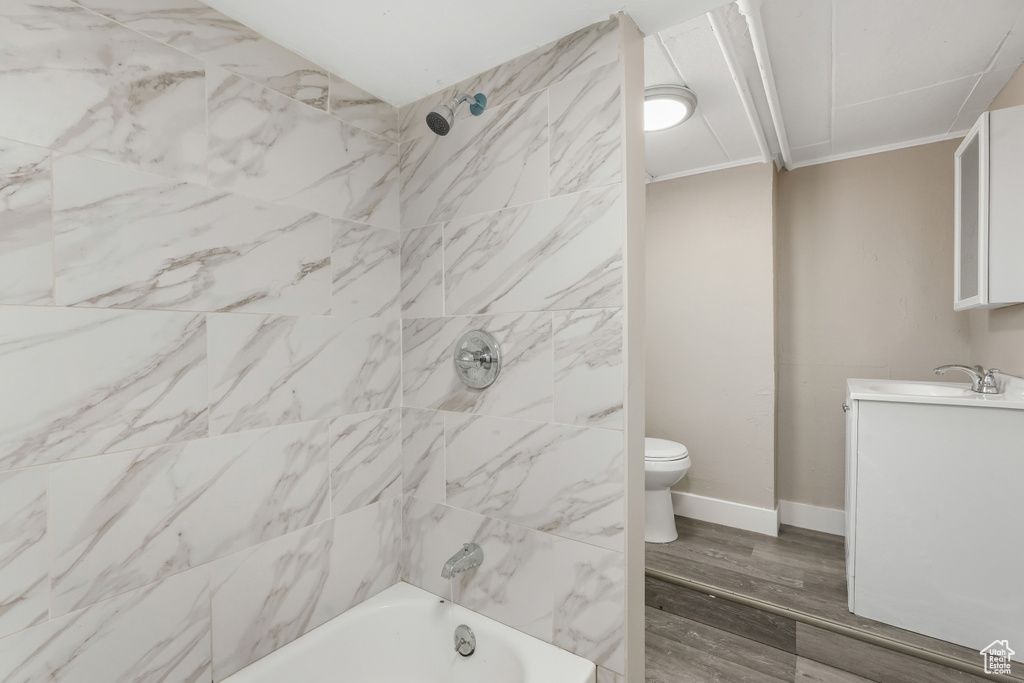 Full bathroom featuring crown molding, toilet, tiled shower / bath, vanity, and hardwood / wood-style floors