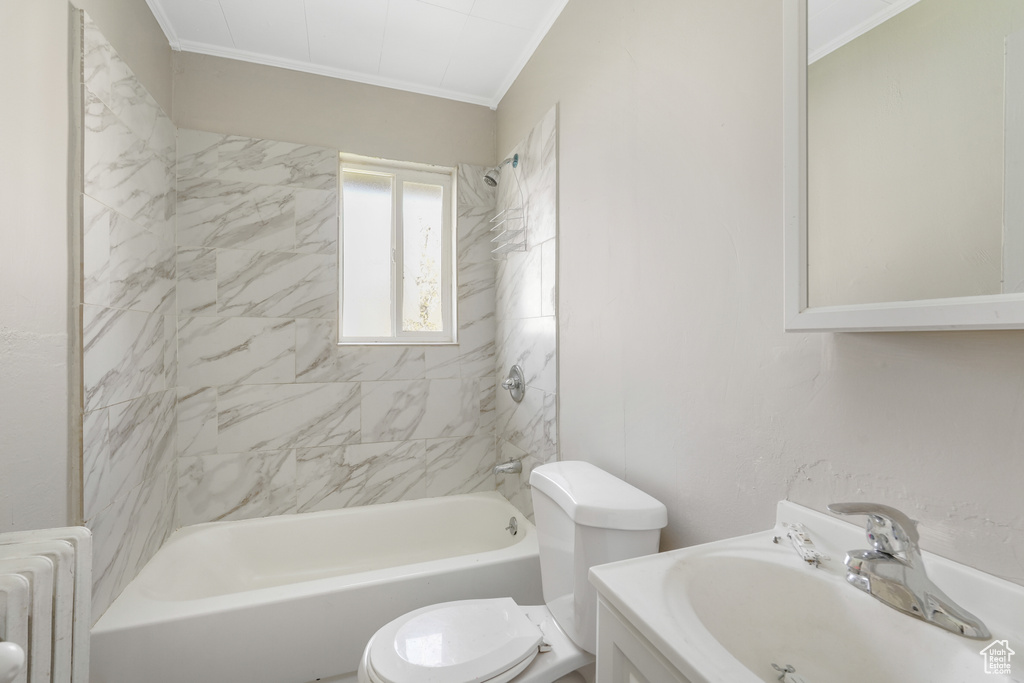 Full bathroom with tiled shower / bath, toilet, radiator heating unit, and sink