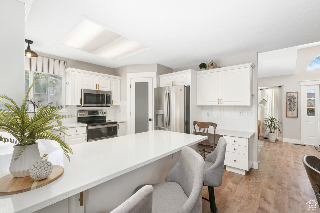Kitchen with plenty of natural light, stainless steel appliances, white cabinetry, and light wood-type flooring