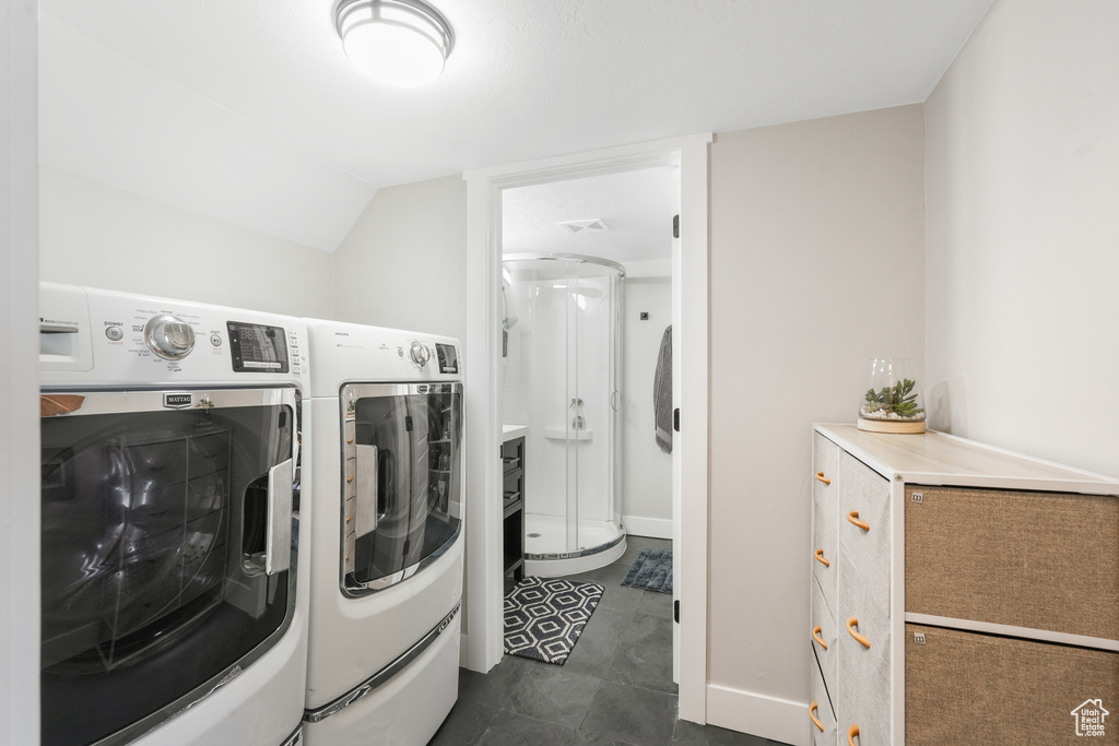 Laundry room featuring independent washer and dryer and dark tile flooring