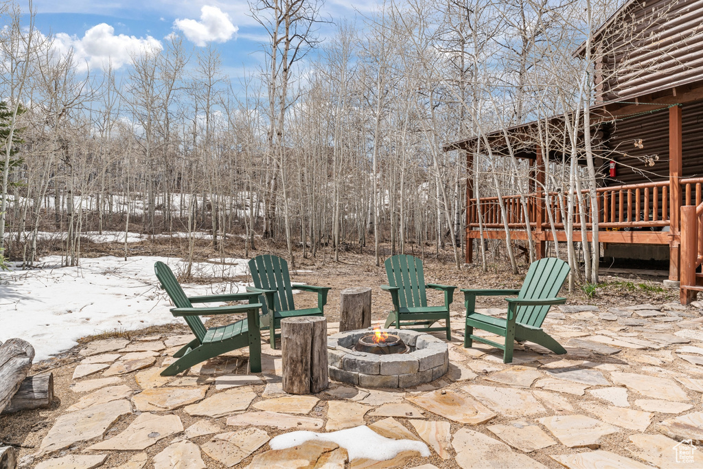 Snow covered patio with an outdoor fire pit and a wooden deck