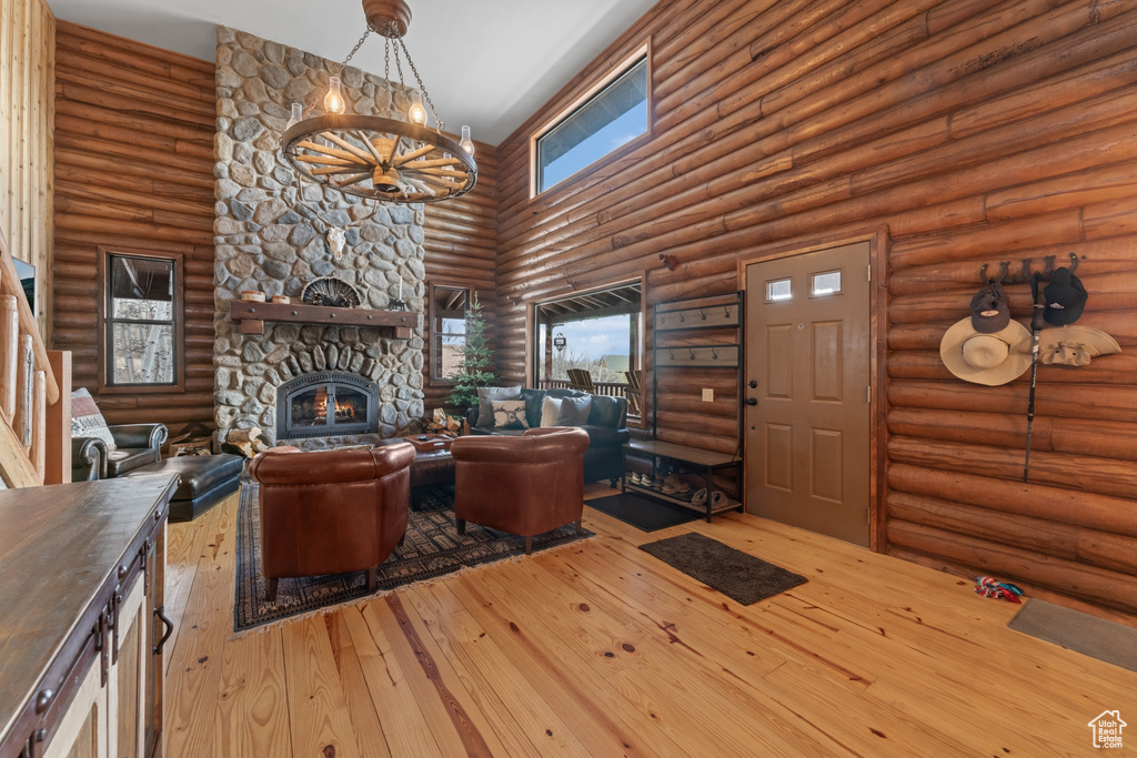 Living room with a fireplace, hardwood / wood-style floors, a high ceiling, and rustic walls