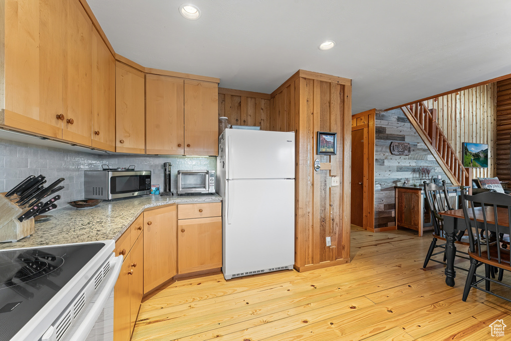 Kitchen with backsplash, light hardwood / wood-style floors, and white refrigerator