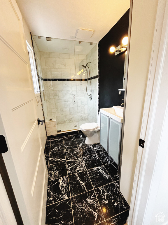 Bathroom with tile flooring, vanity, toilet, and a shower with shower door