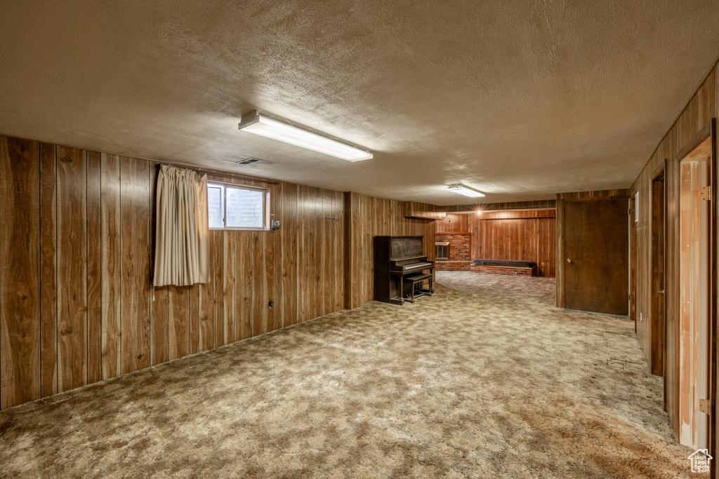 Basement featuring wooden walls, carpet floors, and a textured ceiling