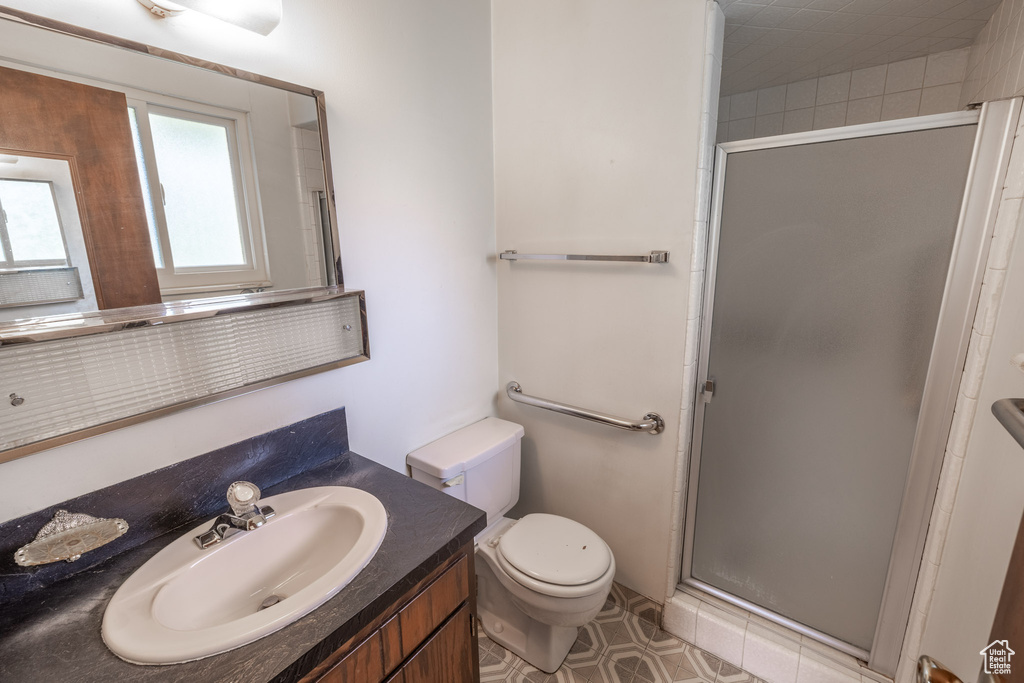 Bathroom featuring tile flooring, oversized vanity, an enclosed shower, and toilet