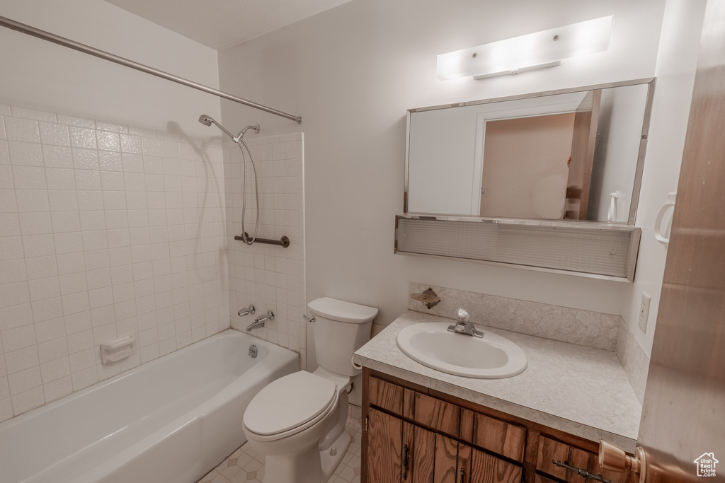 Full bathroom with vanity, toilet, tile floors, and tiled shower / bath combo