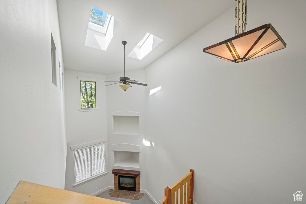 Stairway featuring a skylight, ceiling fan, and a tiled fireplace